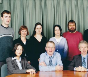 Group of people sitting and standing behind a table